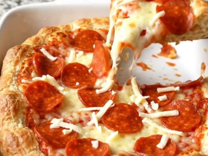 A golden brown Crescent Roll Pizza Bake in a rectangular ceramic dish, topped with bubbling cheese and pepperoni.