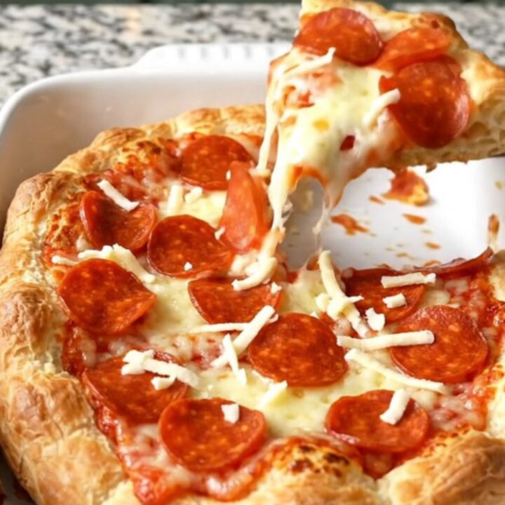 A golden brown Crescent Roll Pizza Bake in a rectangular ceramic dish, topped with bubbling cheese and pepperoni.