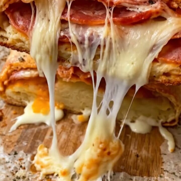 A sliced pepperoni stromboli with stretchy melted cheese on a rustic wooden board.