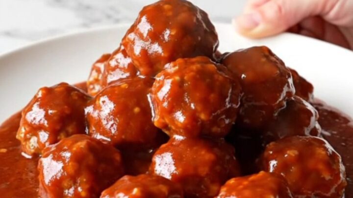 A close-up of turkey meatballs glazed in a glossy, dark red gochujang sauce inside a slow cooker insert.