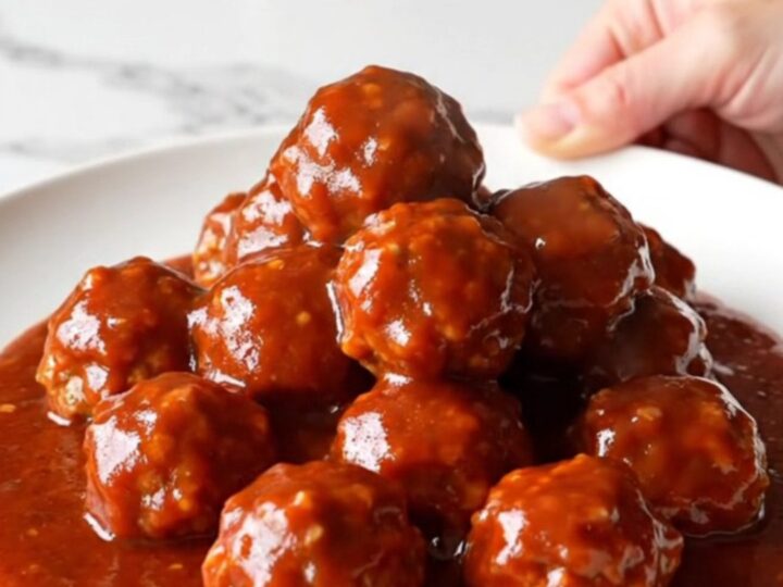 A close-up of turkey meatballs glazed in a glossy, dark red gochujang sauce inside a slow cooker insert.