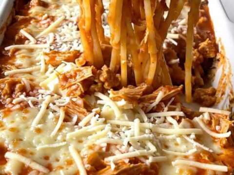 A top-down view of a million dollar spaghetti bake in a white ceramic dish, featuring creamy pockets and turkey marinara.
