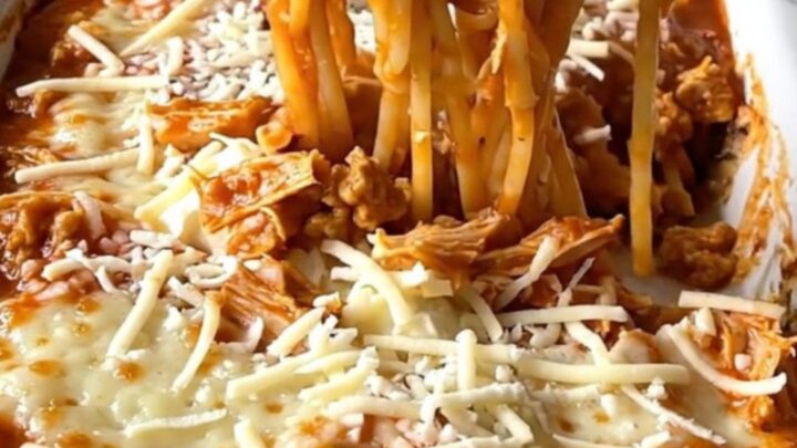 A top-down view of a million dollar spaghetti bake in a white ceramic dish, featuring creamy pockets and turkey marinara.