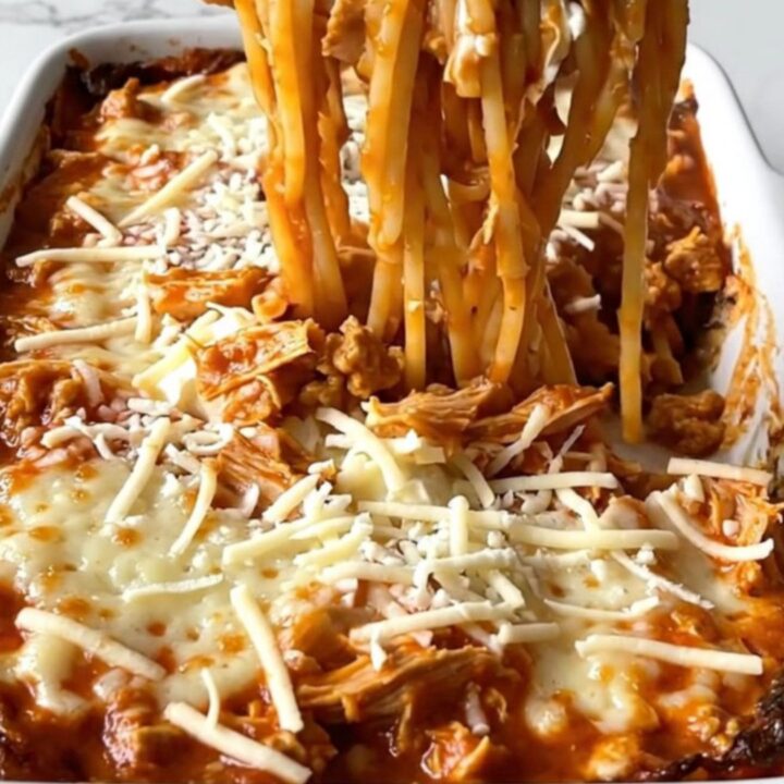 A top-down view of a million dollar spaghetti bake in a white ceramic dish, featuring creamy pockets and turkey marinara.