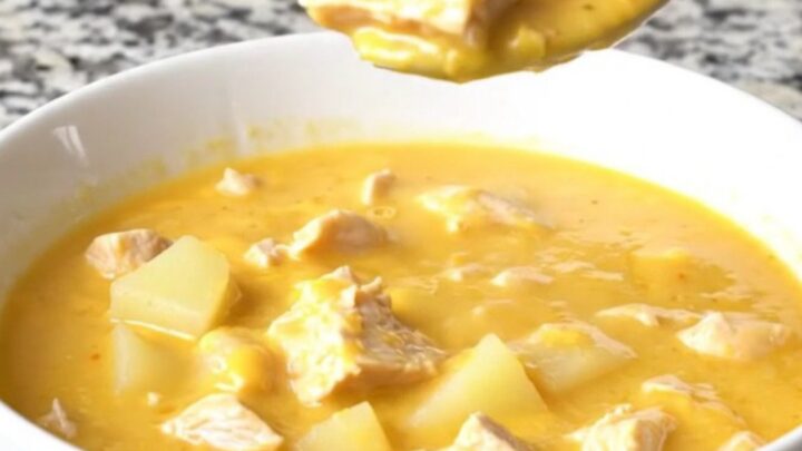 A bowl of creamy cheesy chicken potato soup with chunks of chicken and potatoes, garnished with fresh herbs.