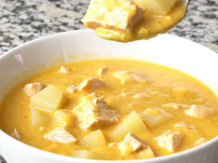 A bowl of creamy cheesy chicken potato soup with chunks of chicken and potatoes, garnished with fresh herbs.