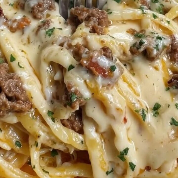 A steaming bowl of linguine tossed in a rich, creamy cheese sauce with browned ground beef crumbles.