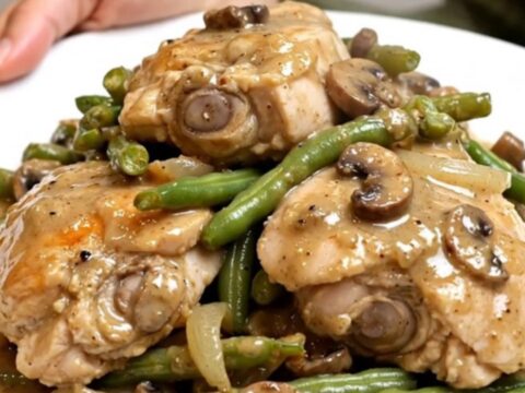 A slow cooker filled with tender chicken thighs, vibrant green beans, and a rich, creamy mushroom sauce