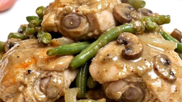 A slow cooker filled with tender chicken thighs, vibrant green beans, and a rich, creamy mushroom sauce