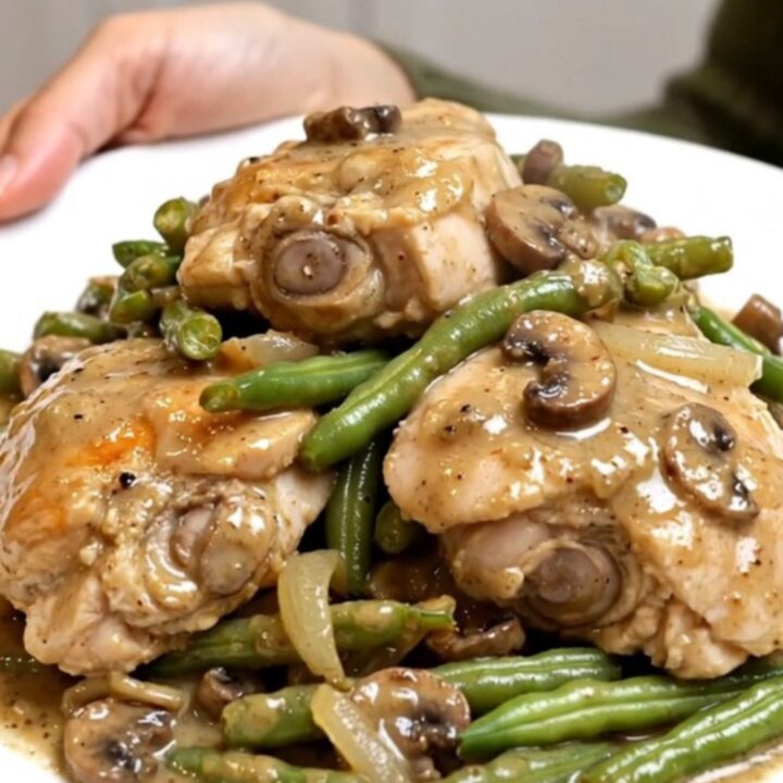 A slow cooker filled with tender chicken thighs, vibrant green beans, and a rich, creamy mushroom sauce