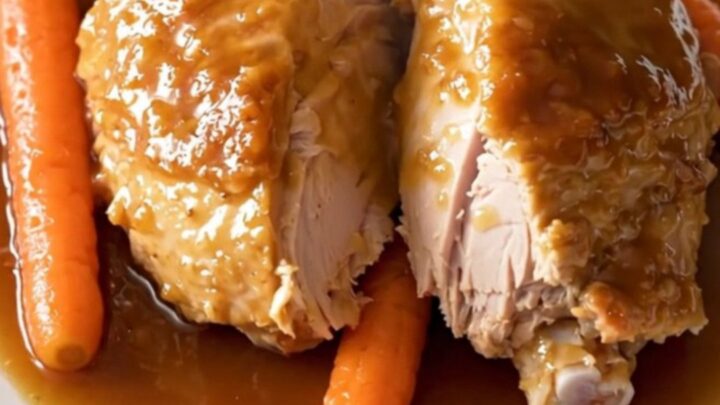 A slow cooker filled with honey garlic turkey tenderloin and baby carrots in a glossy sauce.