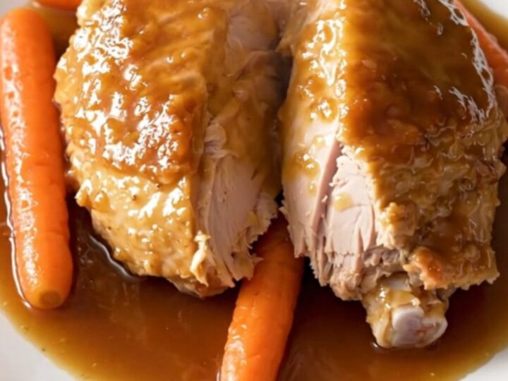 A slow cooker filled with honey garlic turkey tenderloin and baby carrots in a glossy sauce.