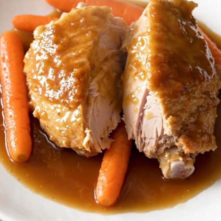 A slow cooker filled with honey garlic turkey tenderloin and baby carrots in a glossy sauce.