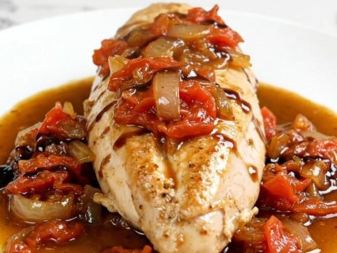Slow cooker bruschetta chicken with stewed tomatoes and balsamic sauce on a white plate.