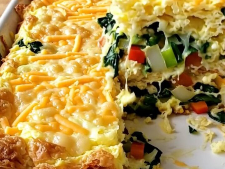 A freshly baked cottage cheese veggie egg bake in a white ceramic dish, featuring colorful peppers, spinach