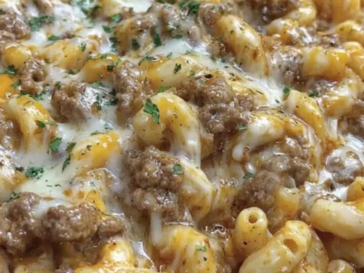 A steaming cast iron skillet filled with creamy cheesesteak hamburger helper, topped with melted cheese and fresh parsley.