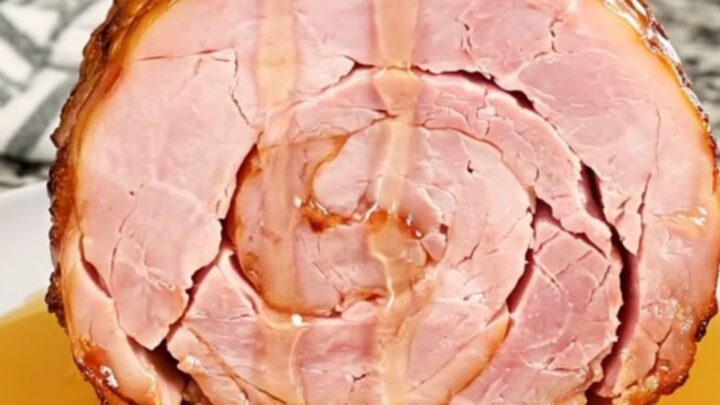 A close-up of a spiral-cut ham in a slow cooker with a glistening hot honey glaze.