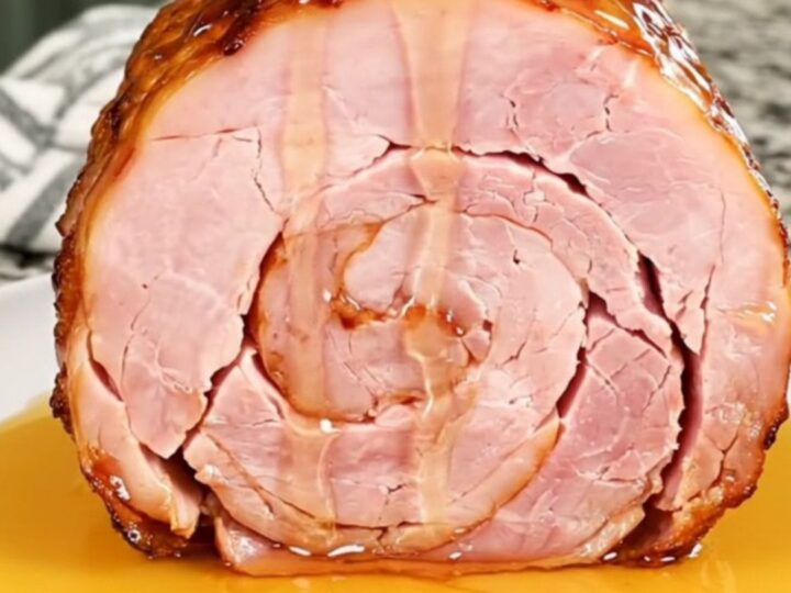 A close-up of a spiral-cut ham in a slow cooker with a glistening hot honey glaze.
