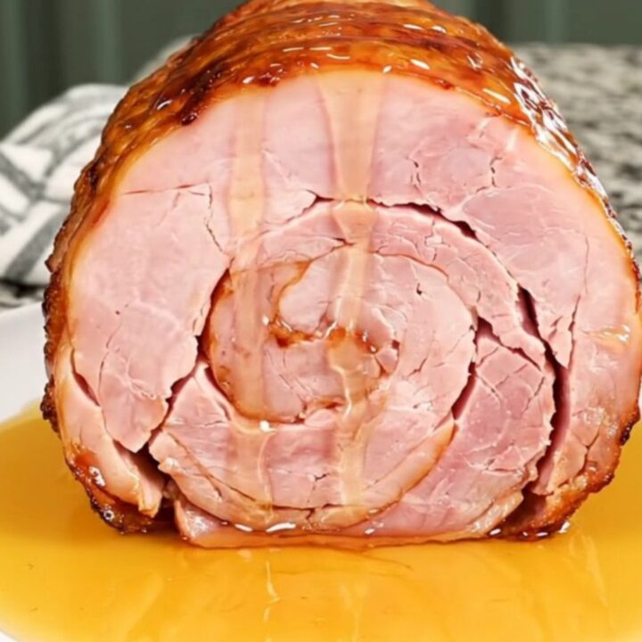 A close-up of a spiral-cut ham in a slow cooker with a glistening hot honey glaze.