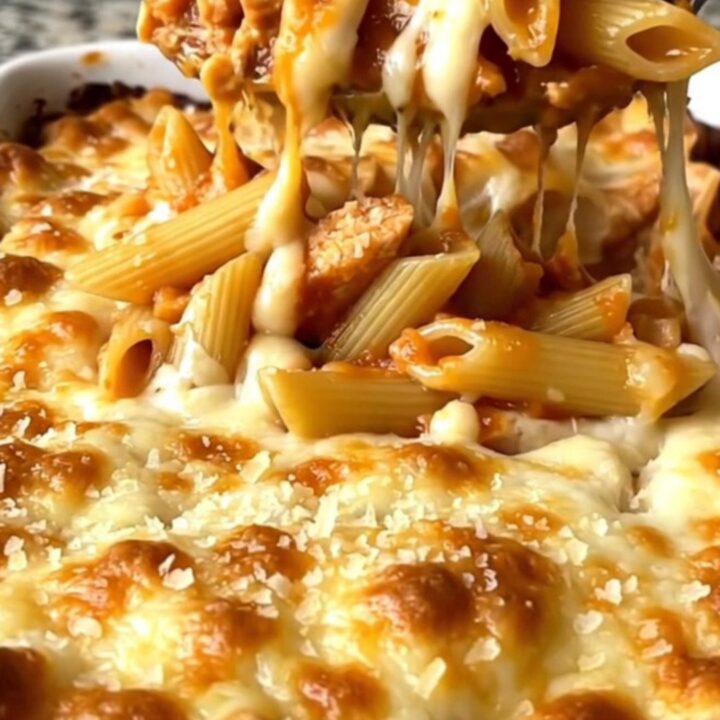 A top-down shot of a rectangular ceramic baking dish filled with pasta, chicken, and melted cheese.