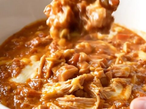 A close-up shot of a white bowl filled with creamy turkey chili, showing a rich texture and steam rising.