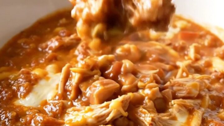 A close-up shot of a white bowl filled with creamy turkey chili, showing a rich texture and steam rising.