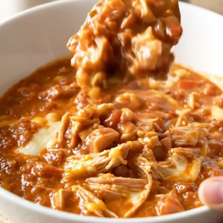 A close-up shot of a white bowl filled with creamy turkey chili, showing a rich texture and steam rising.