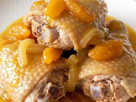 Slow cooker filled with cooked bone-in chicken thighs covered in a rich apricot and onion sauce.