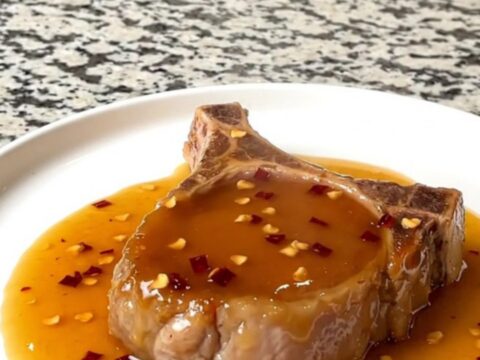 A close-up of tender boneless pork chops glazed in a shiny hot honey sauce in a slow cooker.