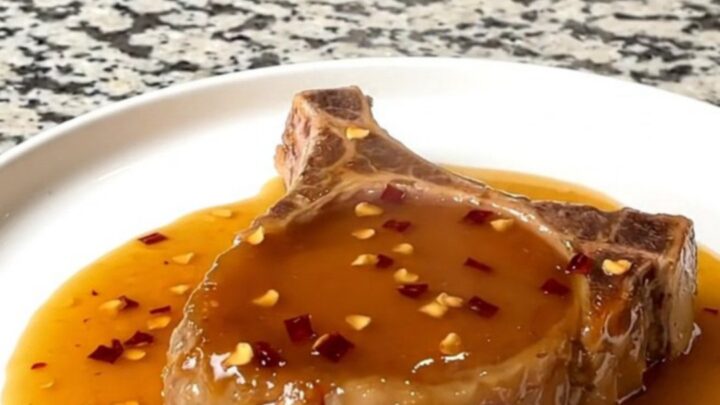 A close-up of tender boneless pork chops glazed in a shiny hot honey sauce in a slow cooker.