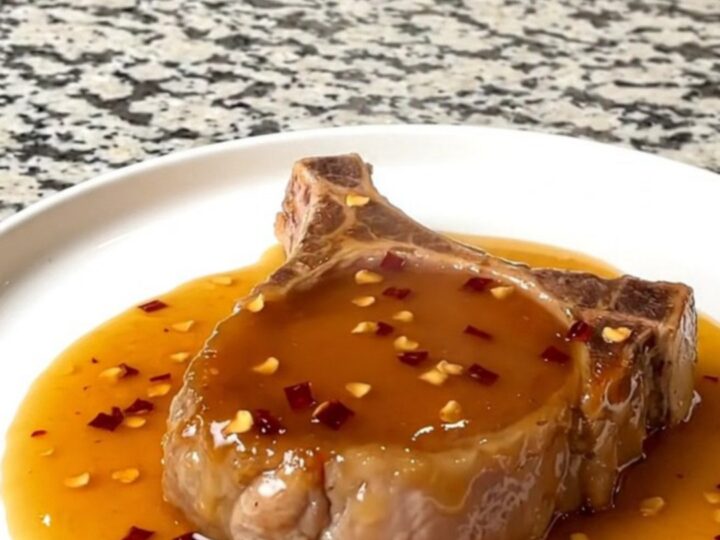 A close-up of tender boneless pork chops glazed in a shiny hot honey sauce in a slow cooker.