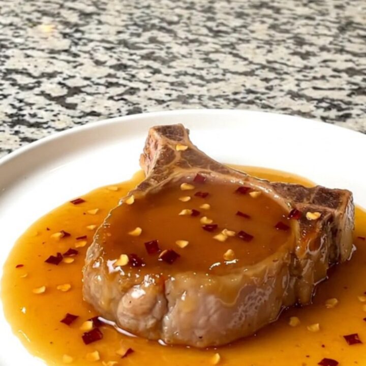 A close-up of tender boneless pork chops glazed in a shiny hot honey sauce in a slow cooker.