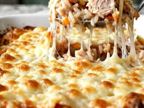 A top-down view of a stuffed pepper casserole with melted mozzarella cheese in a rectangular white baking dish.