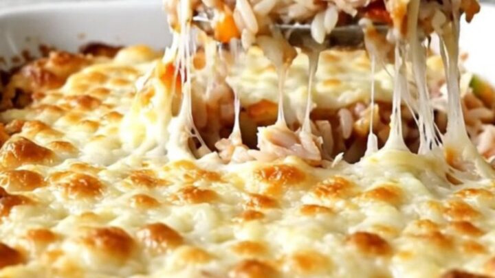 A top-down view of a stuffed pepper casserole with melted mozzarella cheese in a rectangular white baking dish.