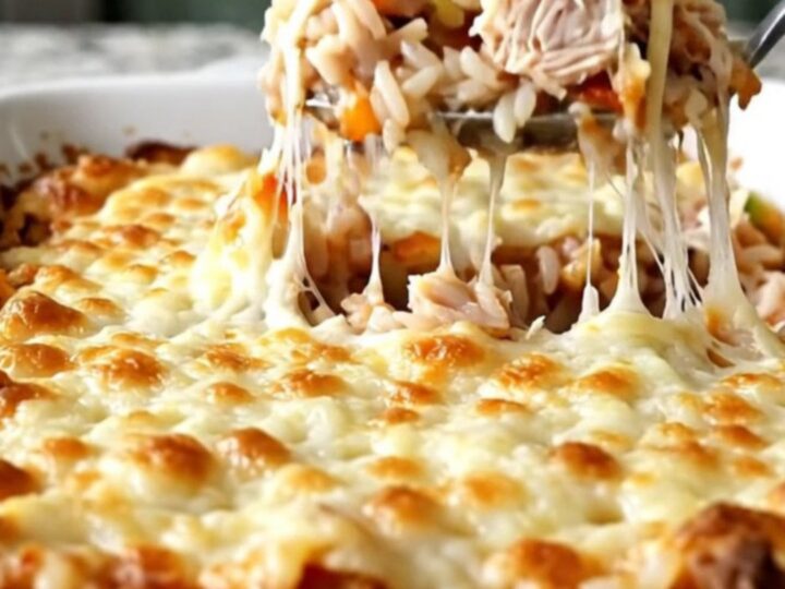 A top-down view of a stuffed pepper casserole with melted mozzarella cheese in a rectangular white baking dish.