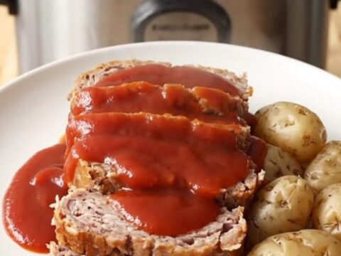 A rustic slow cooker filled with a cooked turkey meatloaf and baby potatoes, ready to be served.