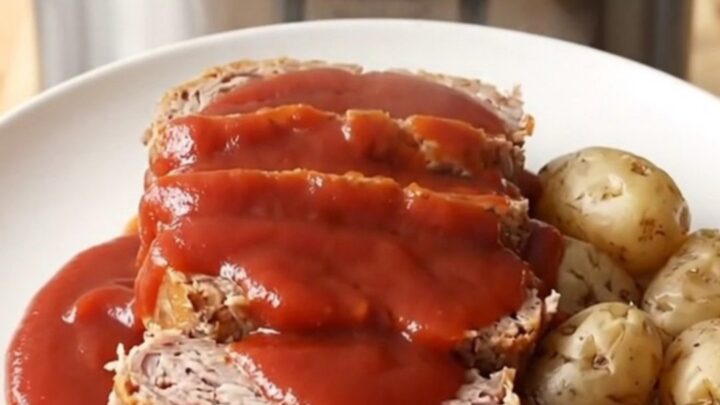 A rustic slow cooker filled with a cooked turkey meatloaf and baby potatoes, ready to be served.