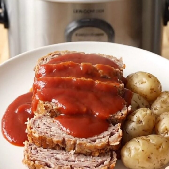 A rustic slow cooker filled with a cooked turkey meatloaf and baby potatoes, ready to be served.