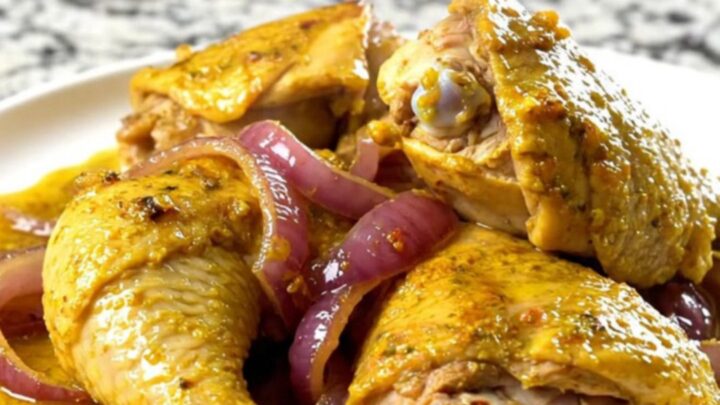 A bowl of tender, yellow-spiced chicken shawarma with soft red onions in a slow cooker.