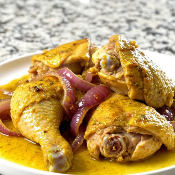 A bowl of tender, yellow-spiced chicken shawarma with soft red onions in a slow cooker.