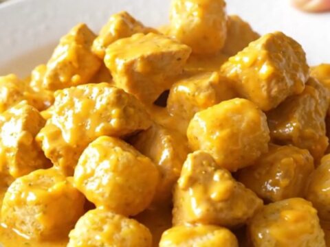 A high-angle shot of a creamy chicken and potato tot casserole in a slow cooker, featuring golden tots and tender chicken.