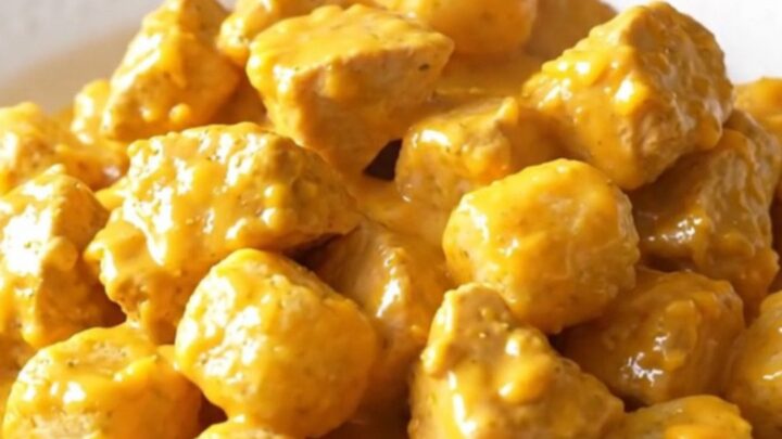 A high-angle shot of a creamy chicken and potato tot casserole in a slow cooker, featuring golden tots and tender chicken.