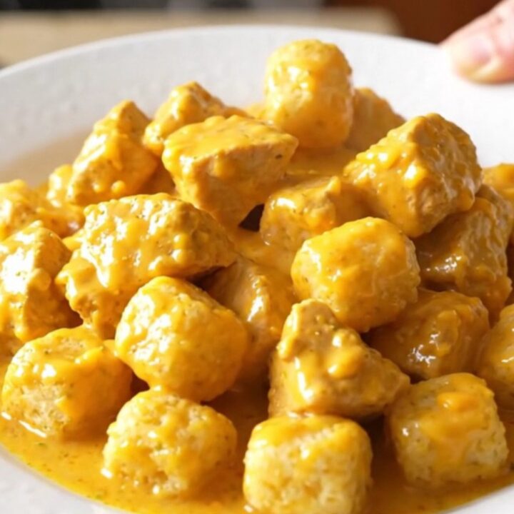 A high-angle shot of a creamy chicken and potato tot casserole in a slow cooker, featuring golden tots and tender chicken.