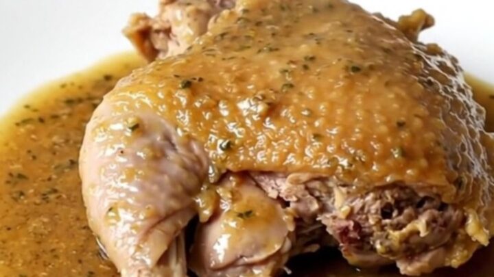 A close-up of a slow cooker filled with braised turkey thighs, carrots, and potatoes in a rich herb gravy.
