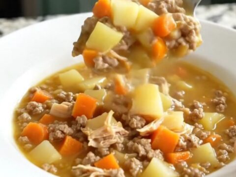A white bowl filled with creamy cheeseburger potato soup topped with ground turkey and carrots.