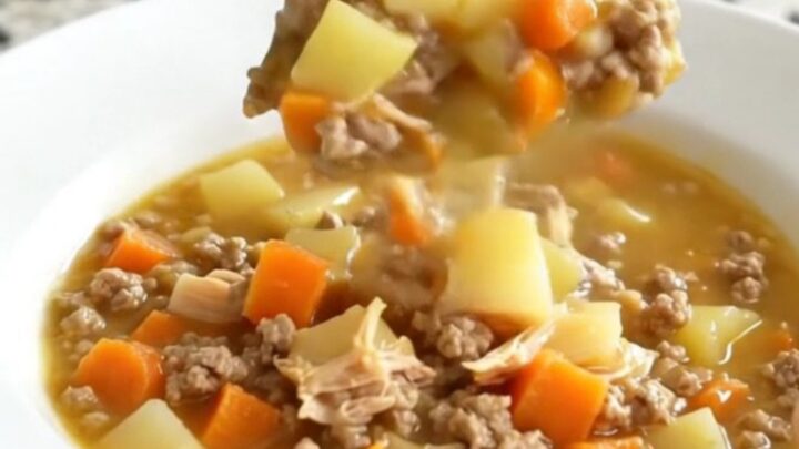 A white bowl filled with creamy cheeseburger potato soup topped with ground turkey and carrots.