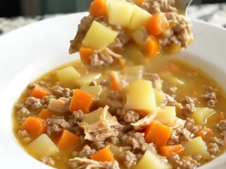 A white bowl filled with creamy cheeseburger potato soup topped with ground turkey and carrots.