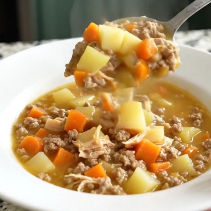 A white bowl filled with creamy cheeseburger potato soup topped with ground turkey and carrots.