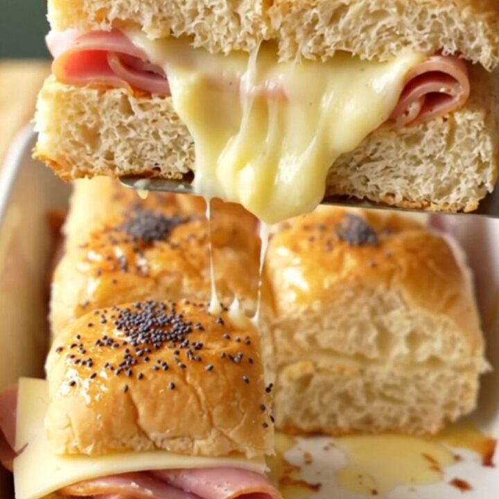A close-up of baked ham and Swiss sliders with golden brown tops sprinkled with poppy seeds.