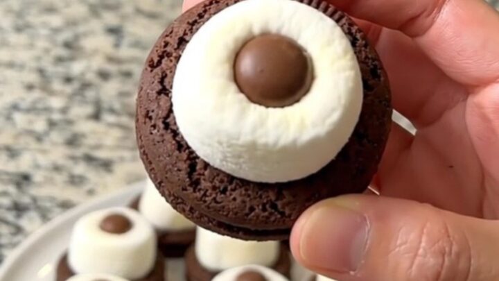 A tray of finished spooky marshmallow eyeball cookies arranged in neat rows on a dark baking sheet.